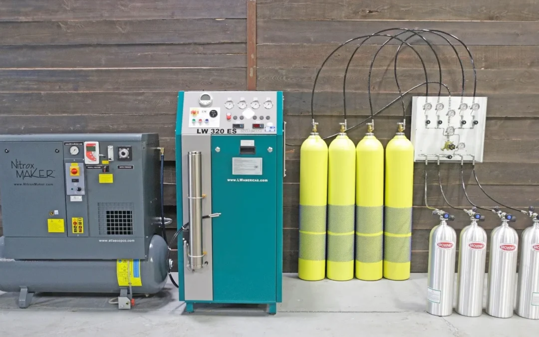 High-pressure breathing-air compressor installation featuring an LW 320 ES compressor from LW Americas connected to a NitroxMaker system on the left, a bank of large yellow storage cylinders in the center, and a fill panel on the right supplying smaller aluminum scuba cylinders labeled “Brownie’s.” The equipment is arranged against a dark wooden wall in a clean workshop setting.